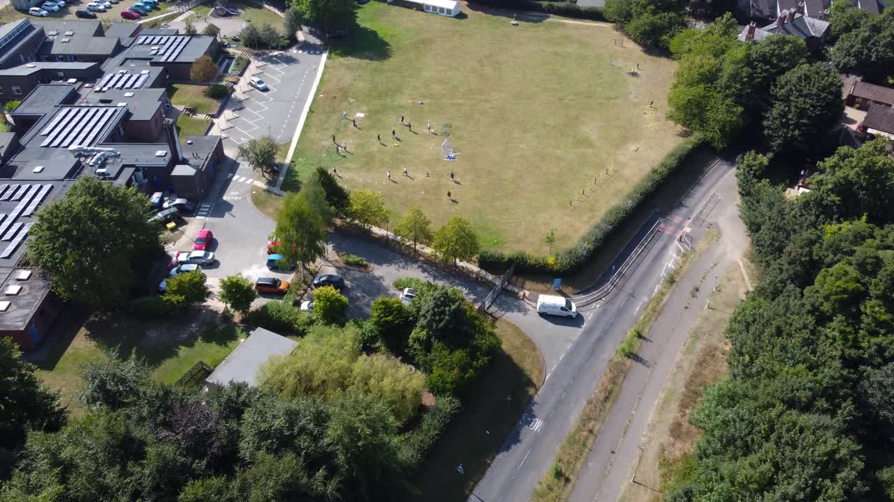 Ripresa aerea: zona residenziale con campo, strada e alberi a Suffolk - inquadratura in avanti con drone.