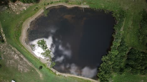 Hyperlapse-Aus-Der-Luft-Von-Oben-Nach-Unten-über-Einen-Teich-Mit-Geschwollenen-Weißen-Wolken,-Die-Sich-Auf-Der-Oberfläche-Spiegeln