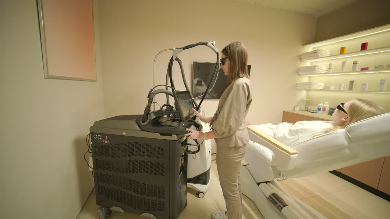 Cosmetologa che utilizza un apparecchio laser per un cliente in una moderna clinica estetica