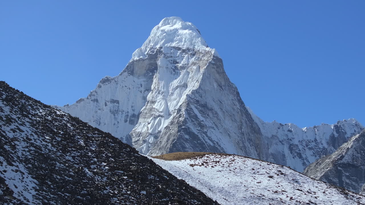 Rivelazione cinematografica del Monte Ama Dablam da un terreno montuoso arido nella regione dell'Everest in Nepal, mostrando vette himalayane spettacolari sotto un cielo alpino limpido