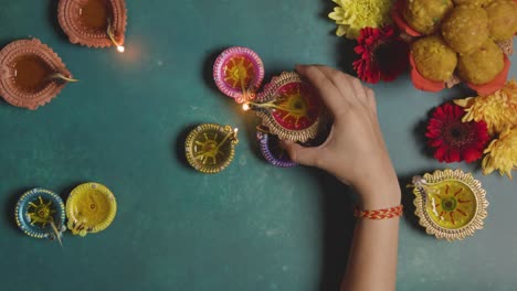 overhead shot of woman lighting diya oil lamps celebrating festival of diwali