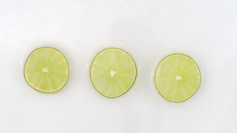 In-slow-motion-water-splashes-pour-water-onto-a-beautiful-juicy-citrus-many-limes-on-a-white-background.-Vegetarian-and-Fructorians.