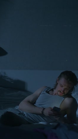 man lying in bed, using smartphone at night