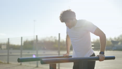 man doing push-ups on parallel bars