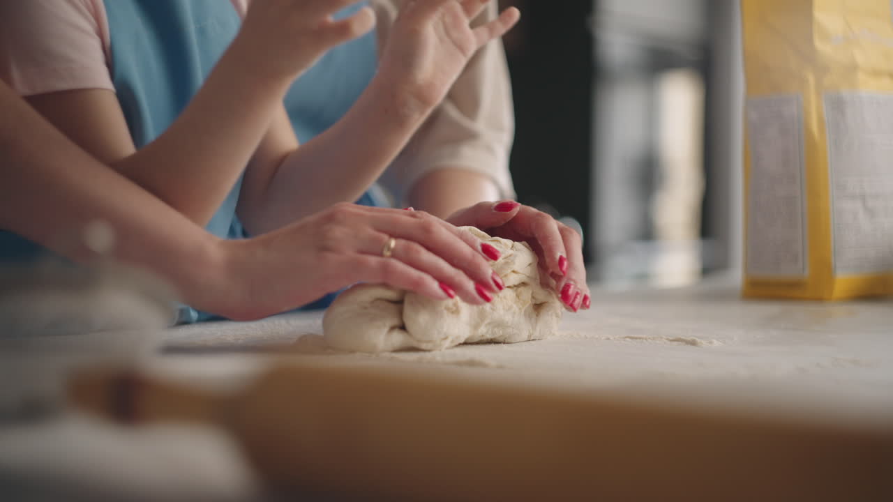 little girl is learning to cook kneading dough for cake or bread mother is helping her daughter closeup