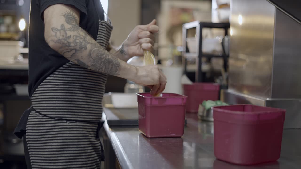 Chef pouring ingredients into containers in a restaurant kitchen