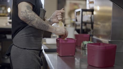 chef pouring ingredients into containers in a restaurant kitchen