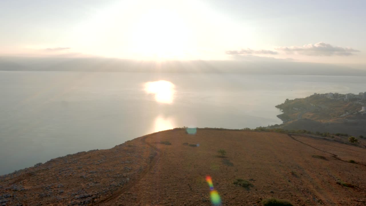 밝은 햇빛이 하늘을 채우고 바다에서 반사되는 하늘에서 내려오는 광선으로 체적 조명을 생성하는 해안 전망