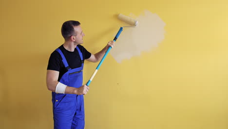 room renovations at home. painter man starts painting wall with a roller on a long handle. professional painting services, contractor.