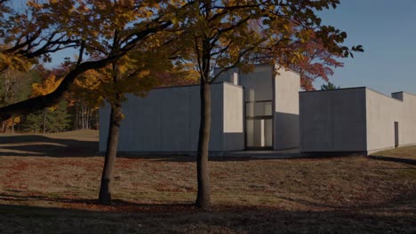 warm sunlight illuminating a contemporary concrete house, nestled among vibrant autumn trees in seoul, creates a serene and picturesque landscape filled with seasonal beauty