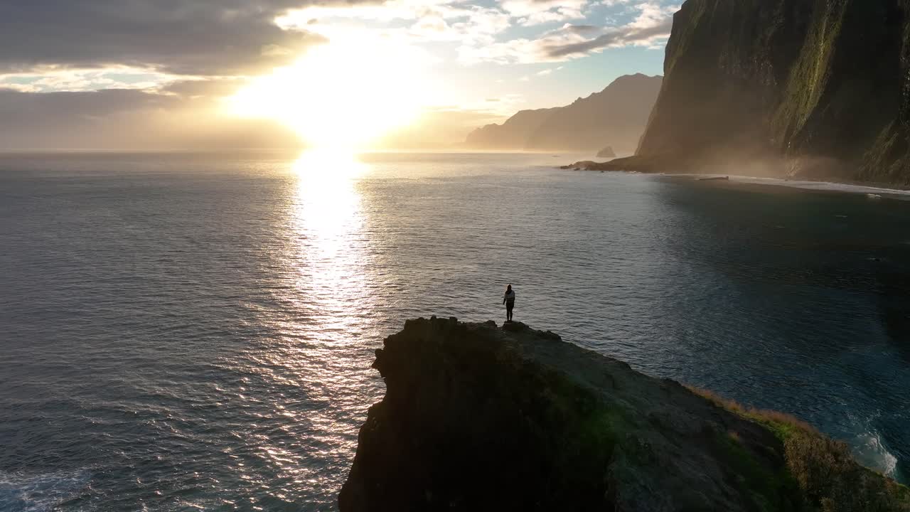Frau geht einen Felsen hinauf mit Blick auf einen wunderschönen Ozean bei Sonnenuntergang, Madeira