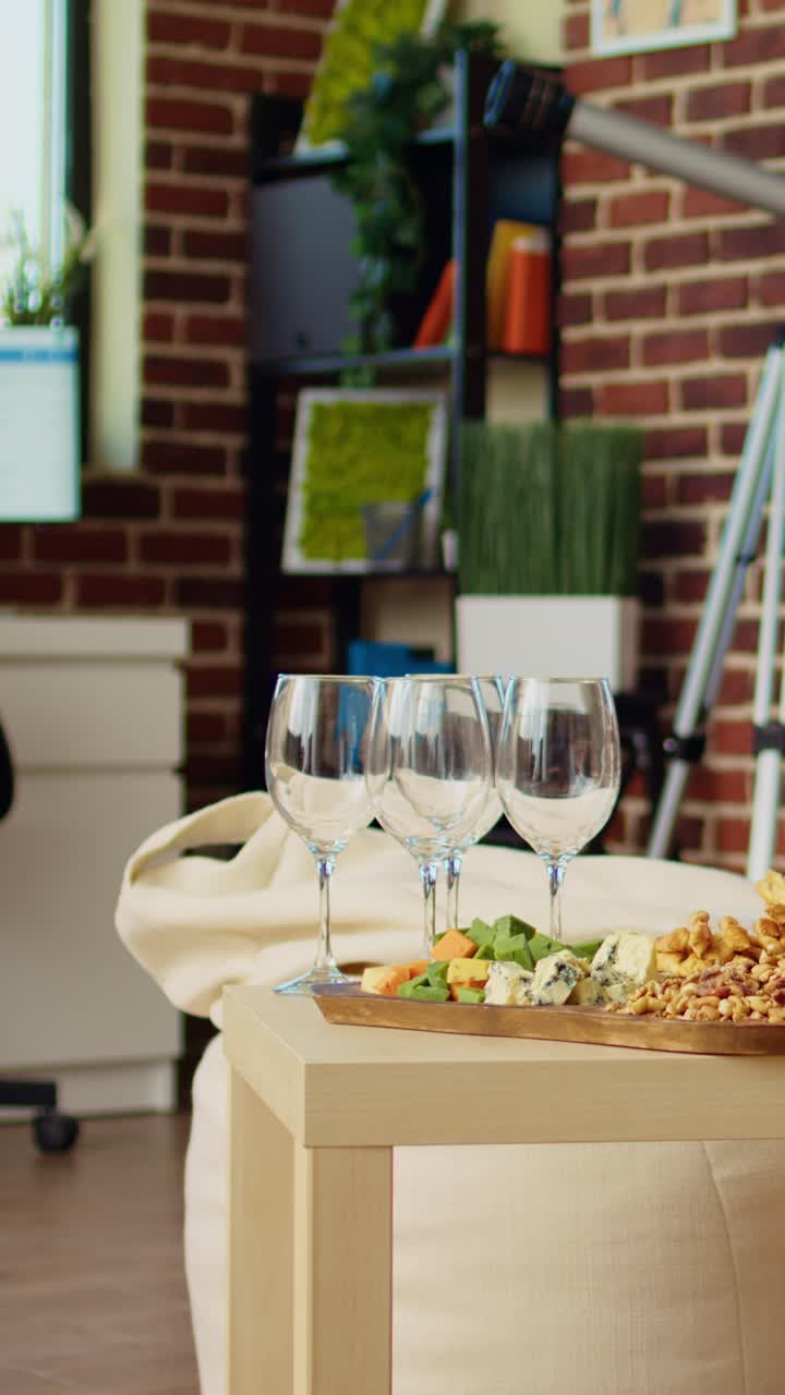Vídeo vertical. Plano panorámico del salón de un apartamento vacío y acogedor con aperitivos y una botella de vino sobre la mesa