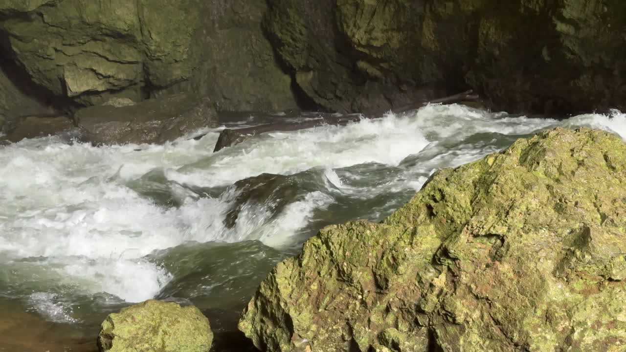 Rushing Rak river water flowing into Weaver Cave in Rakov Skocjan, Slovenia