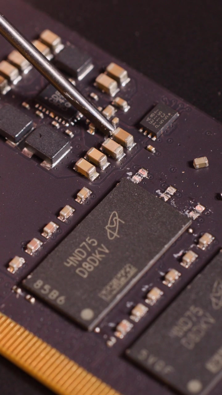 Macro close-up of a metal tool carefully adjusting tiny components on a computer motherboard