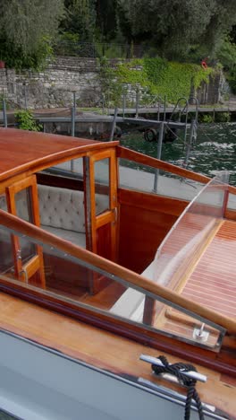 vertical shot of a classic wooden speedboat parked at the dock on lake como, italy (lago di como, italia), evoking timeless luxury and serenity