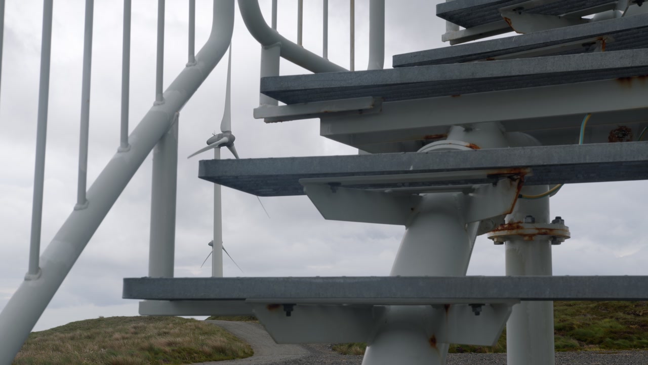 Static shot of wind turbines spinning through industrial steps.