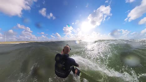 vista fpv posterior de un kitesurfista montando un kiteboard de onda direccional en el océano
