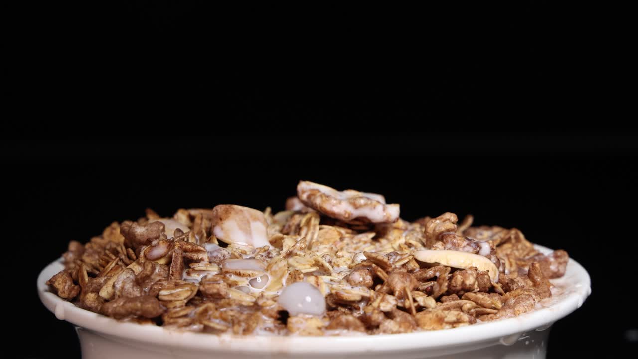 Milk cascades over a bowl of cereal, creating a dynamic and visually appealing overflow effect