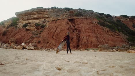 mujer con tabla de surf en la playa
