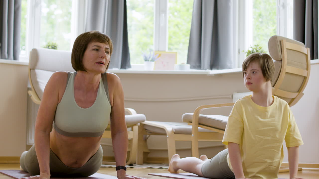 집에서 요가 매트에서 bhujangasana 자세를 취하는 어머니와 딸