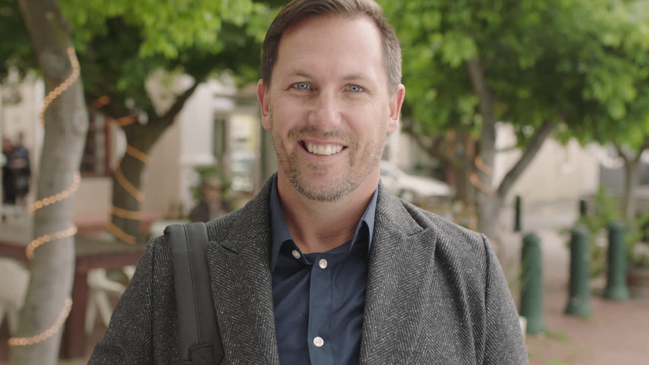 portrait of caucasian businessman looking smiling happy at camera enjoying successful urban lifestyle male commuter wearing coat
