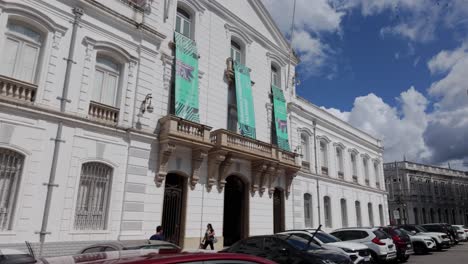 exterior of a white building with banners and cars parked in front