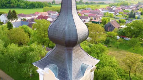 weathered church tower in small township of kormend, hungary, aerial orbit view