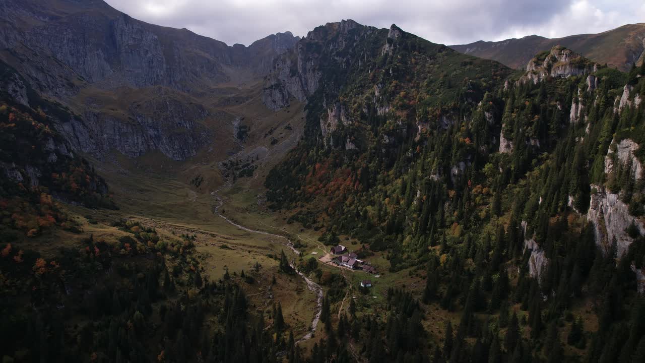 los colores del otoño visten las montañas de bucegi, un chalet remoto anidado en el valle, una toma aérea