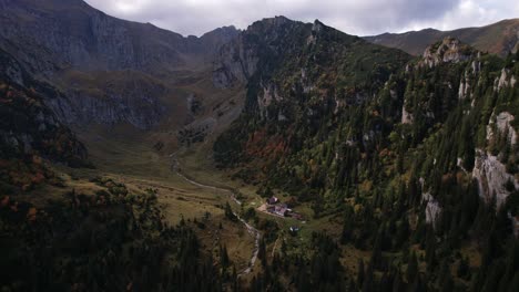 Los-Colores-Del-Otoño-Visten-Las-Montañas-De-Bucegi,-Chalet-Remoto-Enclavado-En-El-Valle,-Toma-Aérea