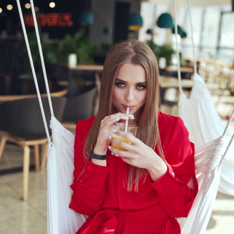 portrait of sexy woman on a swing. beautiful young lady drinking juice while sitting in a cafe and looking at camera.