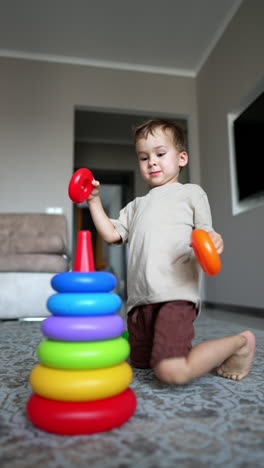 active caucasian toddler builds a pyramid. lovely baby boy plays at home cheerfully. vertical video.
