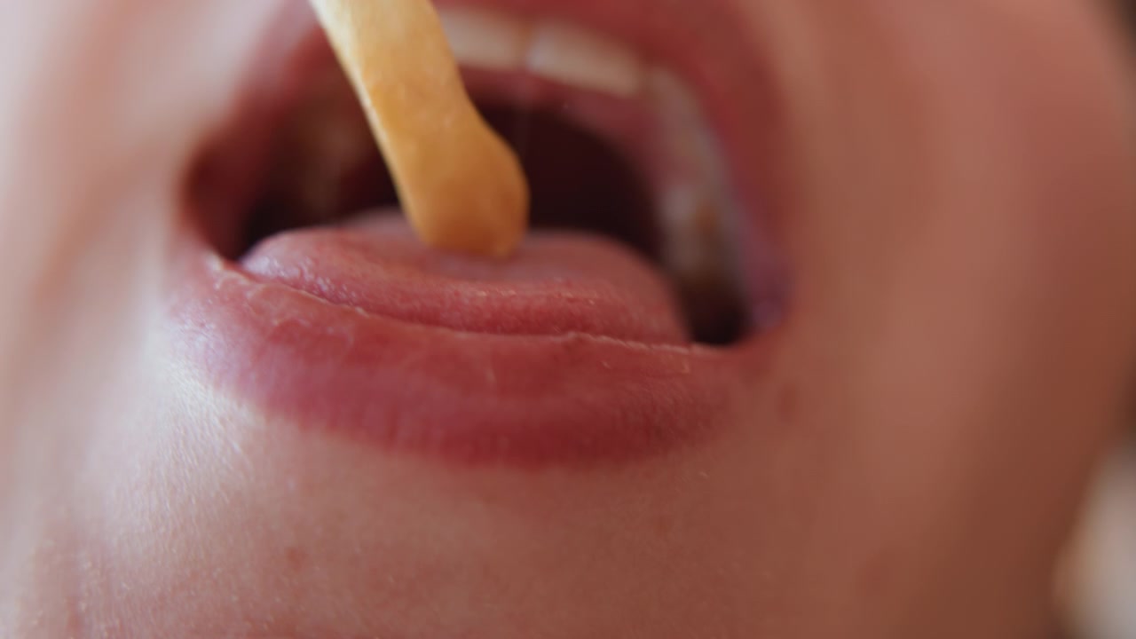 Close-up apertado em ângulo baixo da metade inferior de um rosto adulto mostrando lábios pressionados e depois relaxando em um leve sorriso, com um breve movimento de morder, vinco no queixo, textura de pele macia e luz natural suave