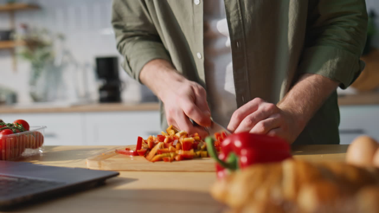Guy hands cutting red bell pepper on wooden board at home kitchen closeup