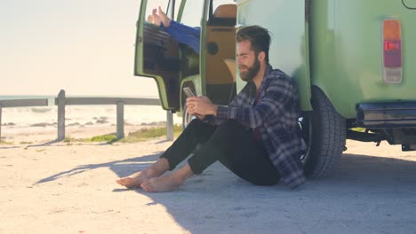 joven enviando mensajes de texto por teléfono móvil cerca de la furgoneta 4k