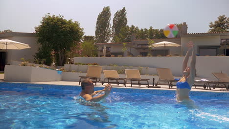 hombre y mujer jugando con la pelota en la piscina