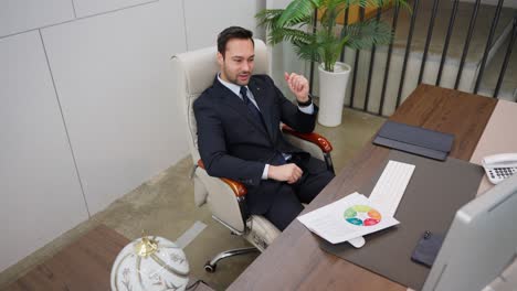 a thoughtful businessman executive in formal suit sits in a modern office chair, intently focused on a computer display while analyzing a colorful chart in a professional and organized workspace