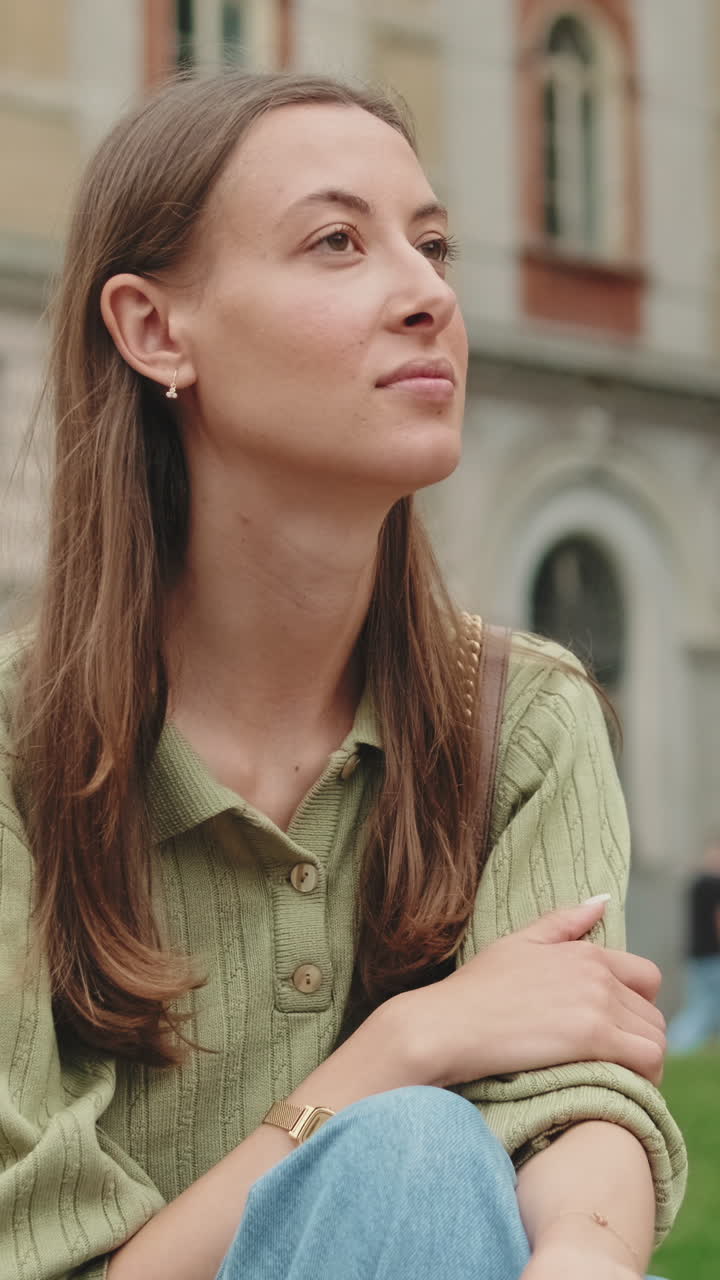 Joven pensativa mirando hacia arriba y sonriendo al aire libre