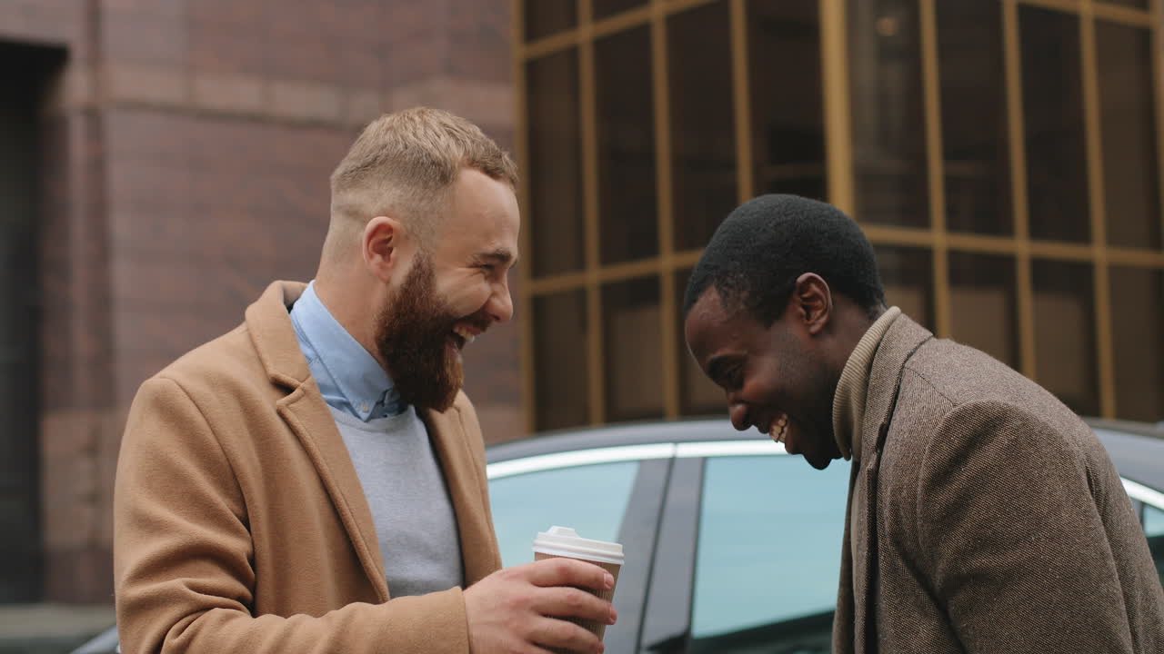 Close-up view of caucasian and African American businessman laughing while they having a nice talk in the street in autumn