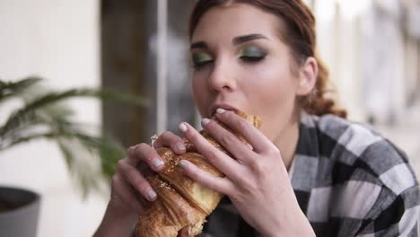 slow motion of a seductive girl takes a croissant in her hands and gently bites it with her eyes closed in pleasure. wiggle with enjoyment and taste. close up