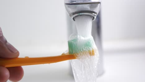 washing a toothbrush under running water