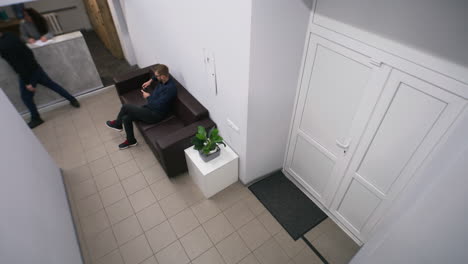 overhead view of a man sitting on a sofa in a modern waiting area