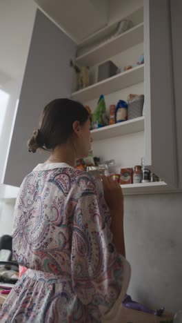 woman reaching for items in kitchen cabinet