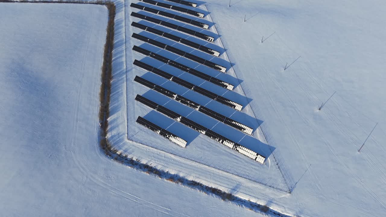 Solární panely částečně pokryté sněhem během chladných zimních podmínek, letecký pohled, tenký sloupec.