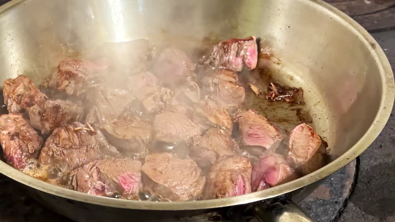 Cubes of beef red meat cooking simmering on high heat in giant pot close-up