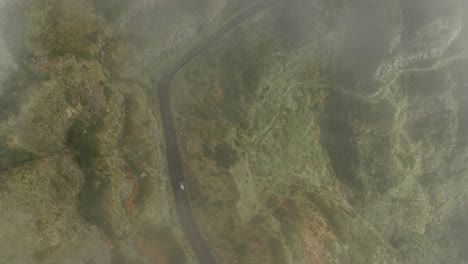 por encima de la conducción de automóviles a través de un terreno montañoso escarpado, revelar un disparo a través de la niebla, antena