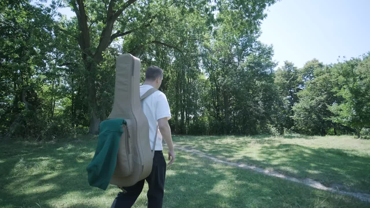 숲 근처의 거리에서 기타를 들고 는 젊은 남자