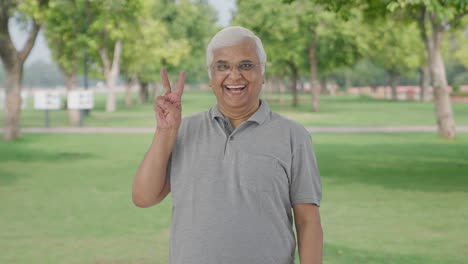 Indian-old-man-showing-victory-sign-in-park