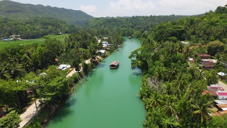 4k drone video of a scenic view as a boat floats down a tropical river in bohol, philippines