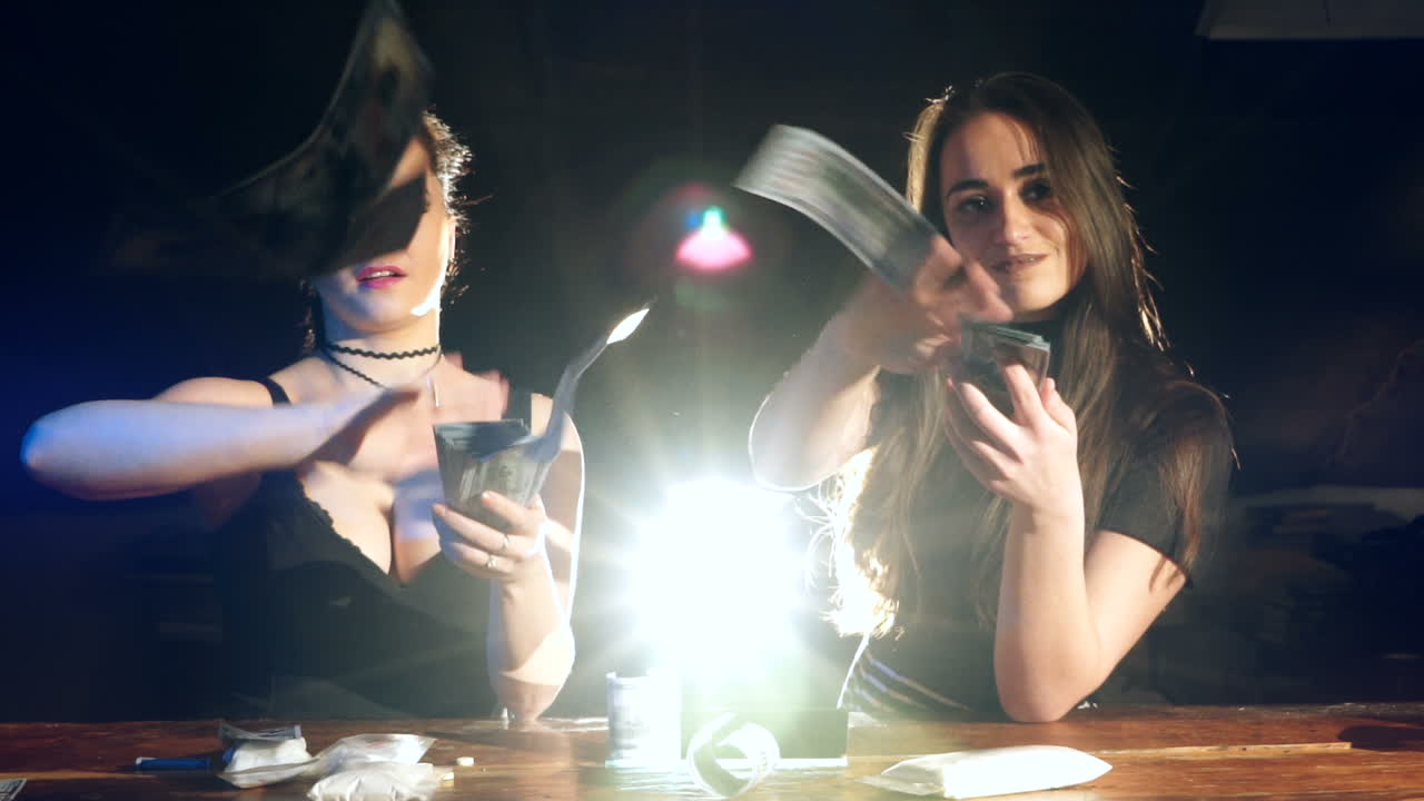 Two young female laughing and throwing american dollars in the air. Slow motion. Criminal Business