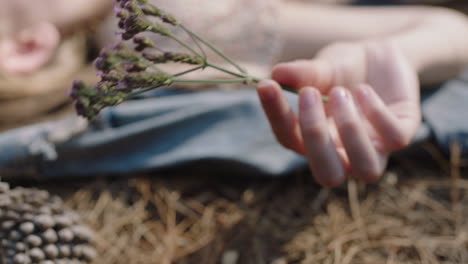 woman holding flower lying on ground in forest woods